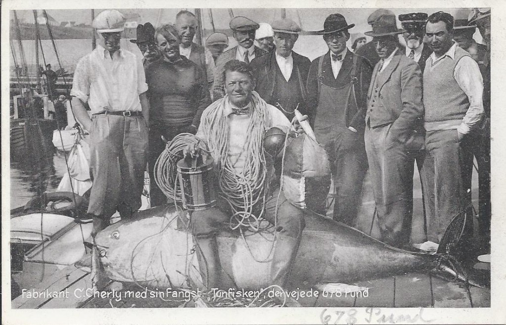Fabrikant C.Cherly med sin rekord fisk, bagerst med kasket, ses havnefoged Nikolaj Andersen. Postkortet har eneretnummeret 74198 - hvilket gør at man kan dateret til det omkring 1940